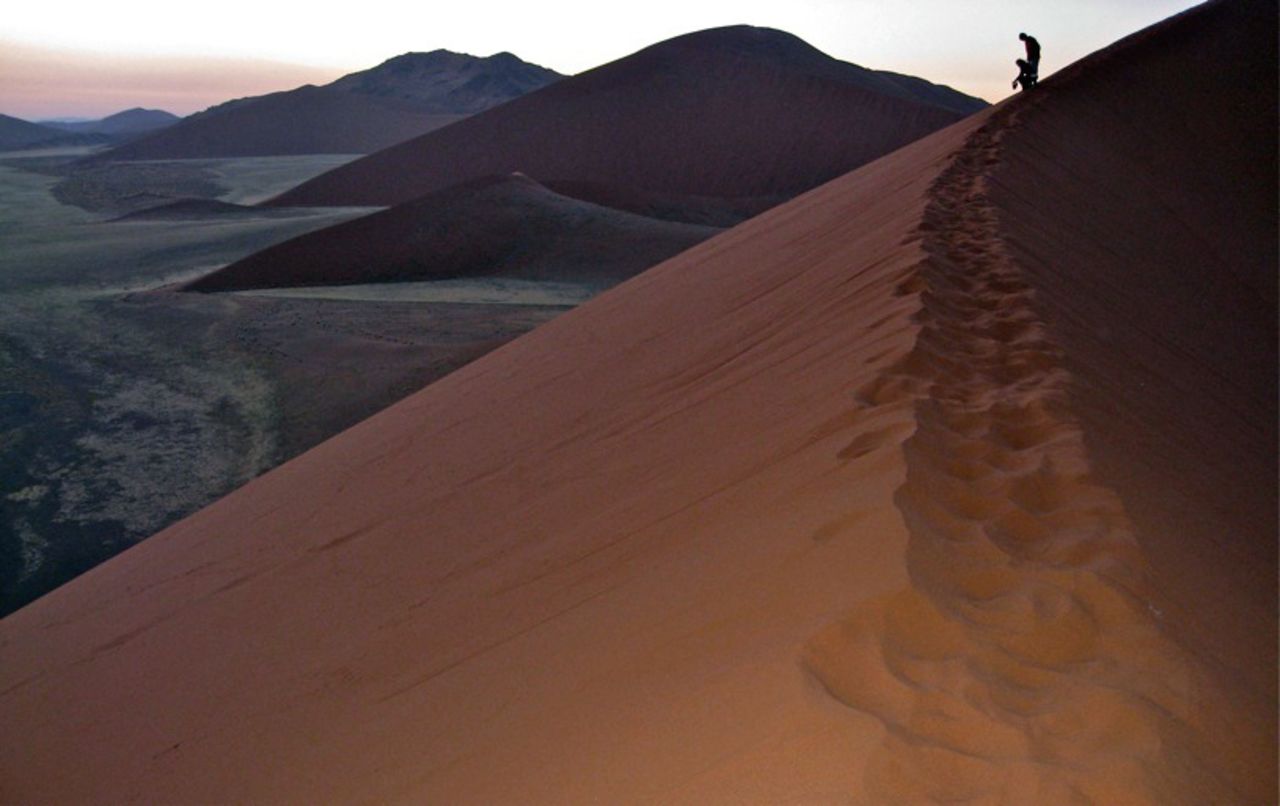 Visitors climb the dunes to catch the sunrise and leave the dramatic Namib-Naukluft National Park before it gets too hot.