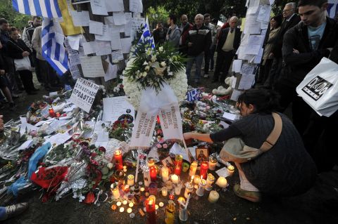 People light candles and lay flowers and hand written messages on April 5, 2012 at the site where a retired pharmacist shot himself at Athens central Syntagma square on April 4, citing the austerity measures as a reason.
