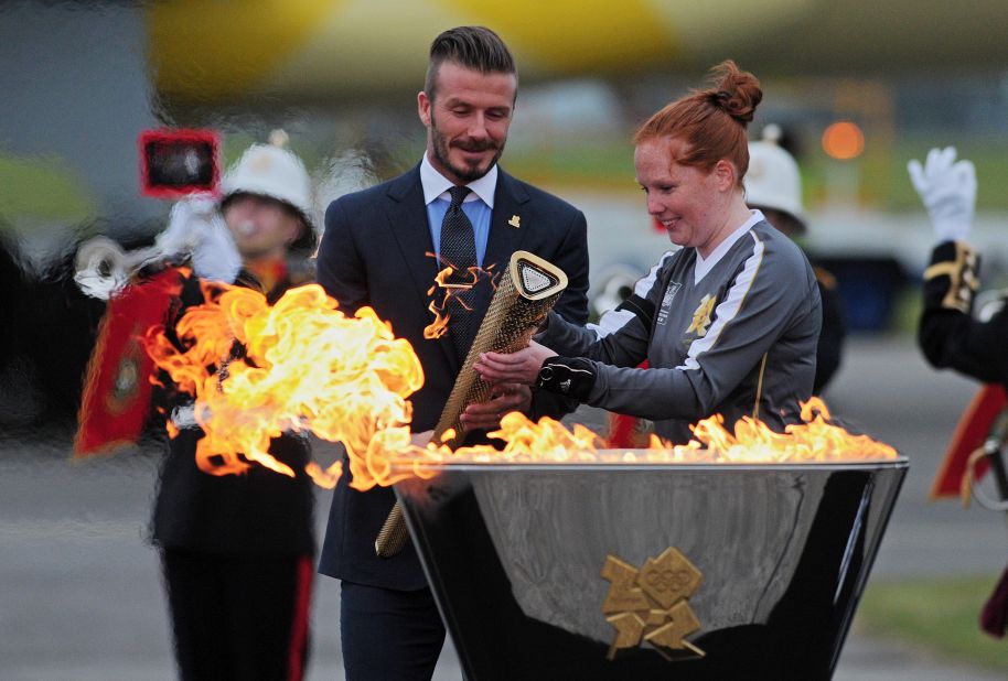 Former England footballer David Beckham, left, lights the Olympic torch upon its arrival at RNAS Culdrose Air Base in Cornwall, southwest England, on Friday, May 18.