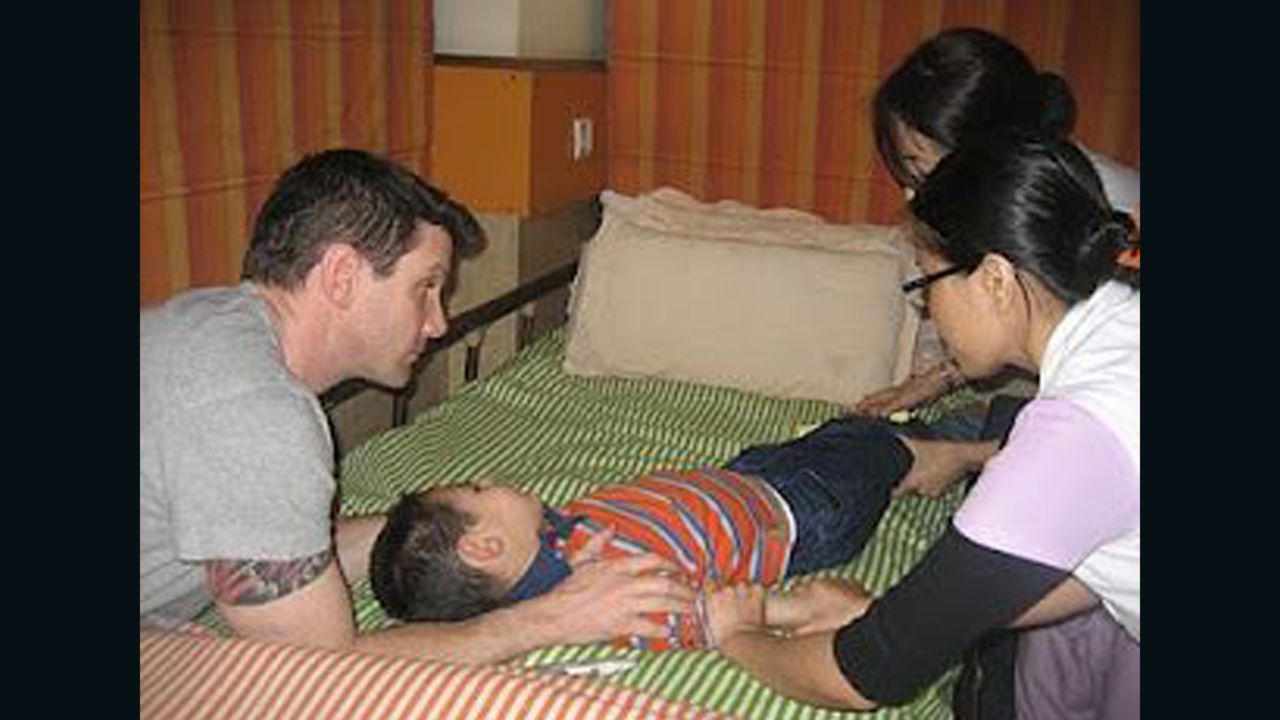 Cash is comforted by his father, Josh Burnaman, while nurses treat the boy during therapy at NuTech Mediworld in 2010.