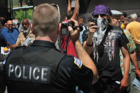 A police officer and a protester face off with cameras in Chicago during a demonstration organized by National Nurses United on Friday, May 18. Friday was the fifth day of protests leading up to the NATO summit.