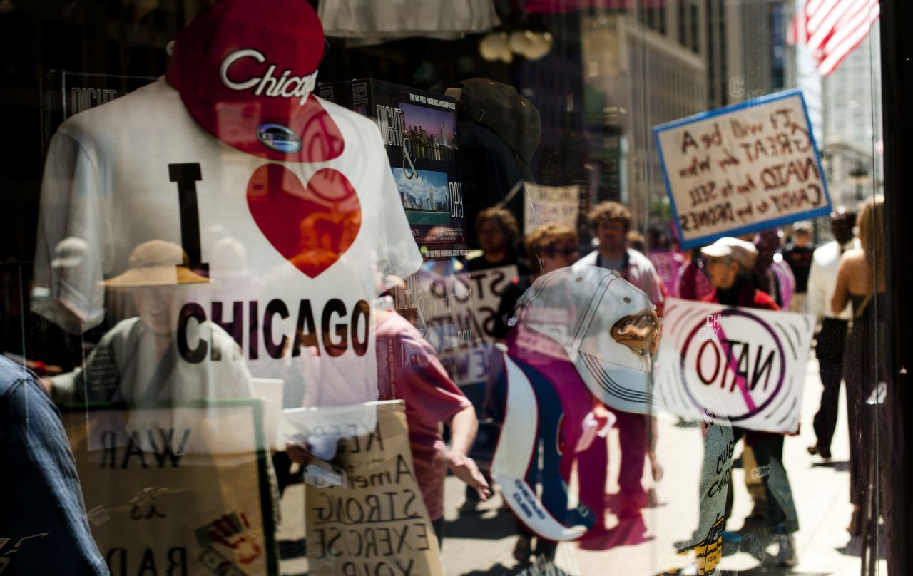 A souvenir shop window reflects protesters in Chicago on Thursday as they demand an end to NATO violence ahead of the summit.