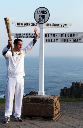Olympic sailor and the first London 2012 torchbearer, Ben Ainslee, poses next to the Land's End sign in Cornwall.