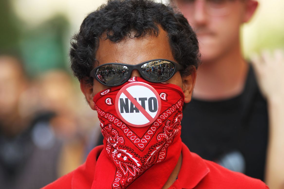 A demonstrator displays an anti-NATO button on his bandana Sunday. Largely peaceful crowds chanted, waved signs and banged drums in Chicago.