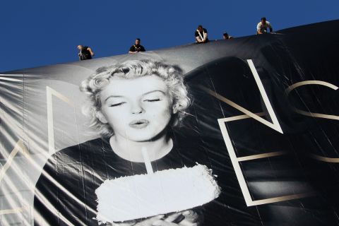 Workers set up a giant poster featuring Marilyn Monroe blowing out a birthday candle on May 13. 