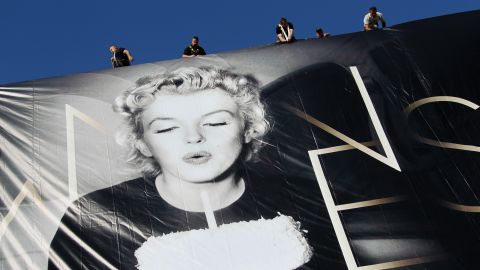 Workers set up a giant poster featuring Marilyn Monroe blowing out a birthday candle on May 13.
