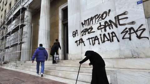 An elderly woman begs by the Bank of Greece headquarters in Athens on February 14, 2012.