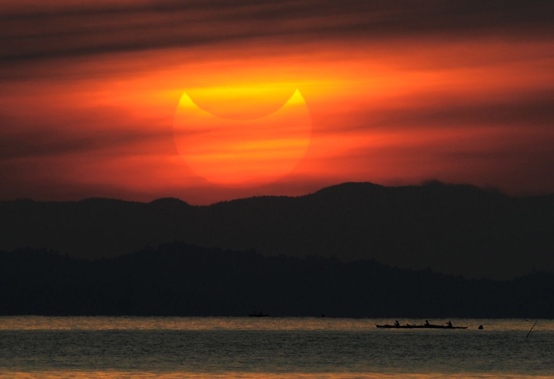A partial solar eclipse is seen at sunrise in the coastal town of Gumaca, Philippines.