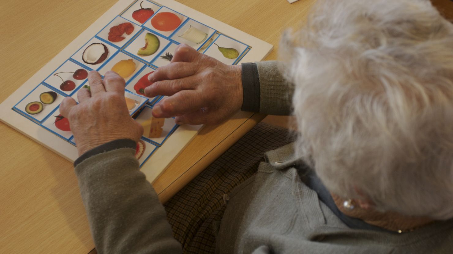 A woman with Alzheimer's at a care center works a puzzle to exercise her mind.