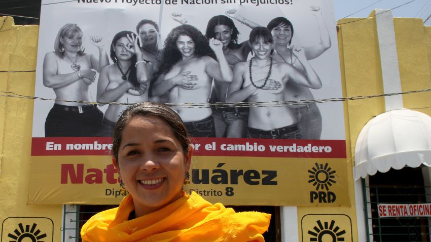 Mexican congressional candidate Natalia Juarez poses in front of a billboard on which she and other women are topless.