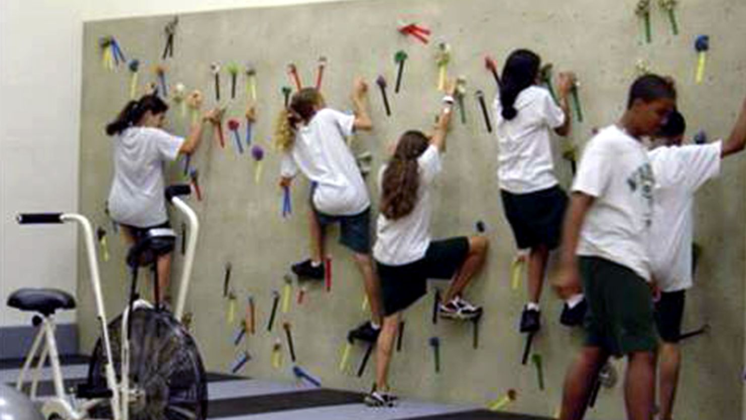 Students at a middle school in Miami climb on a traversing wall in a Fit-Tech Wellness Lab. 