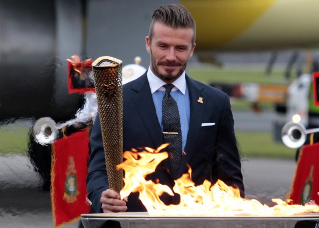 David Beckham lights the torch as it arrives at RNAS Culdrose airbase in Cornwall, England, on May 18. The footballer was part of a British delegation that flew back with the flame from Greece.