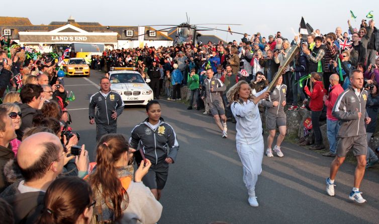 Surfer Tassy Swallow carries the flame as it leaves Land's End. She is one of 8,000 torch-bearers who will transport the flame on its 70-day journey to the Olympic Stadium in east London.
