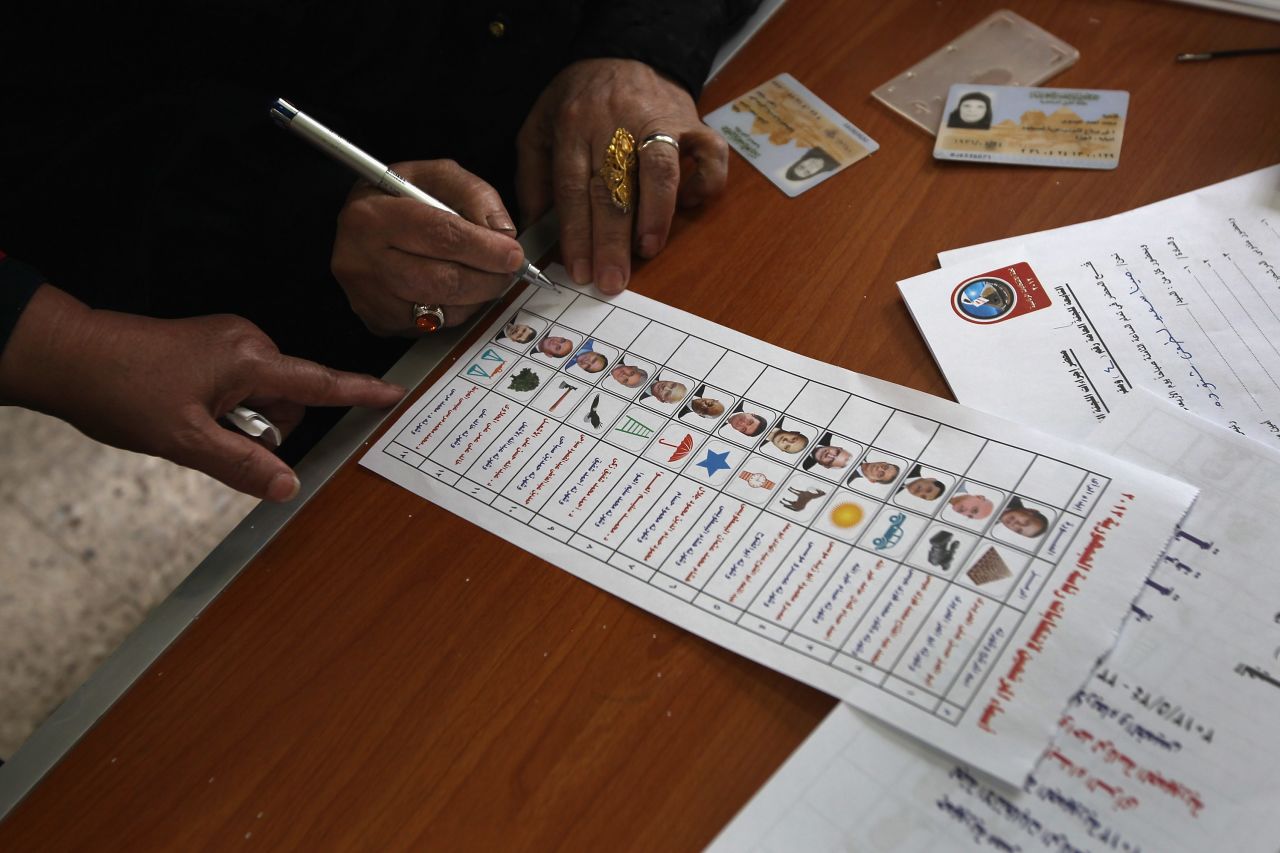 A voter studies her ballot Wednesday in Cairo. Thirteen candidates are competing in the wide-open race, but two withdrew after ballots were printed.