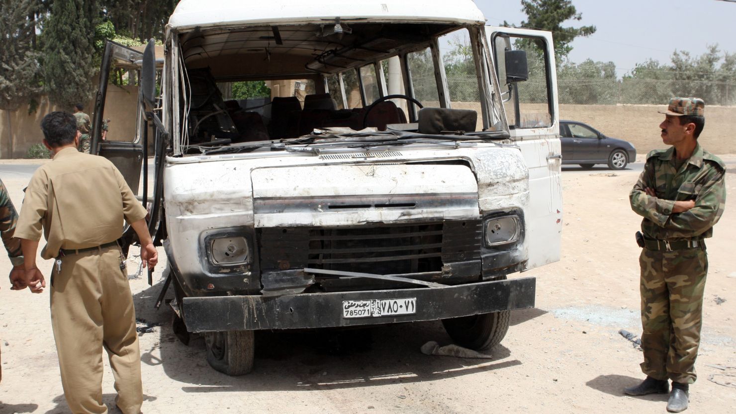 Syrian military officers inspect a damaged bus following a deadly explosion on May 23, 2012.