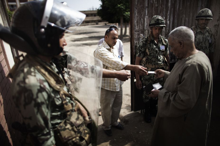 An election worker checks the identification of a voter at a polling place Thursday in Namul as Egyptian soldiers stand guard.