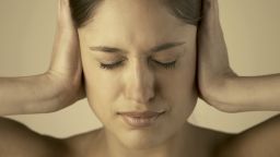 woman hands ears tinnitus