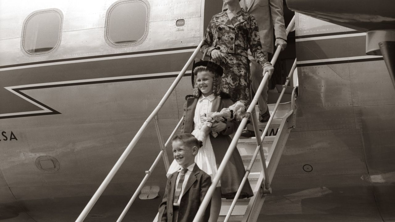 Family walking down airplane stairs circa 1960s