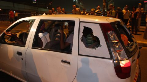 African immigrants drive a car with windows shattered by Israeli protesters in Tel Aviv Wednesday.