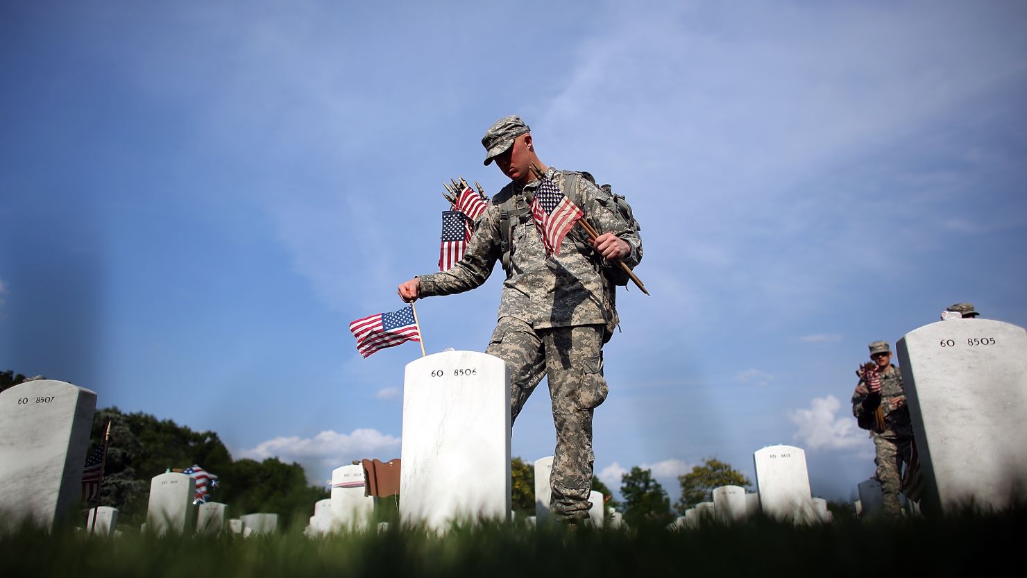 Members of the 3rd US Infantry Regiment place American flags at the graves of US soldiers buried at Arlington National Cemetery.