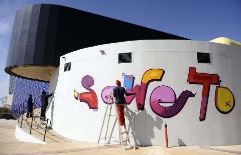 Laborers finish the paintwork on the newly inaugurated Soweto Theater, a powerful symbol of the Johannesburg's rebirth.