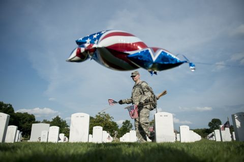 A soldier plants a flag at Arlington National Cemetery on Thursday.