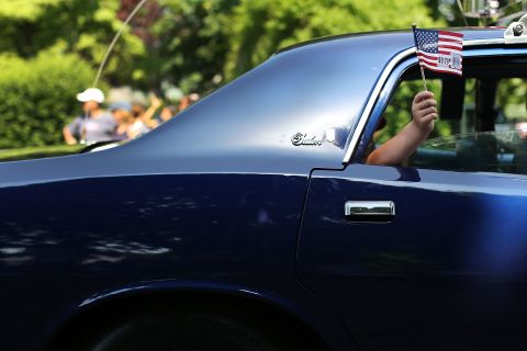 A boy waves an American flag from the window of a car participating in a Memorial Day parade in Fairfield, Connecticut, on Monday, May 28.