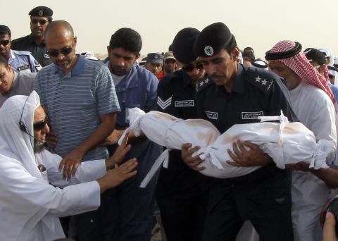 Members of the Qatari civil defense prepare to bury a child in Doha, Qatar, on Tuesday, May 29. A fire broke out at a shopping mall a day earlier, killing 19 people, including 13 children, officials said.