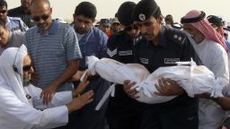 In Doha on May 29, members of the Qatari civil defence prepare to bury a child who perished in a mall fire.