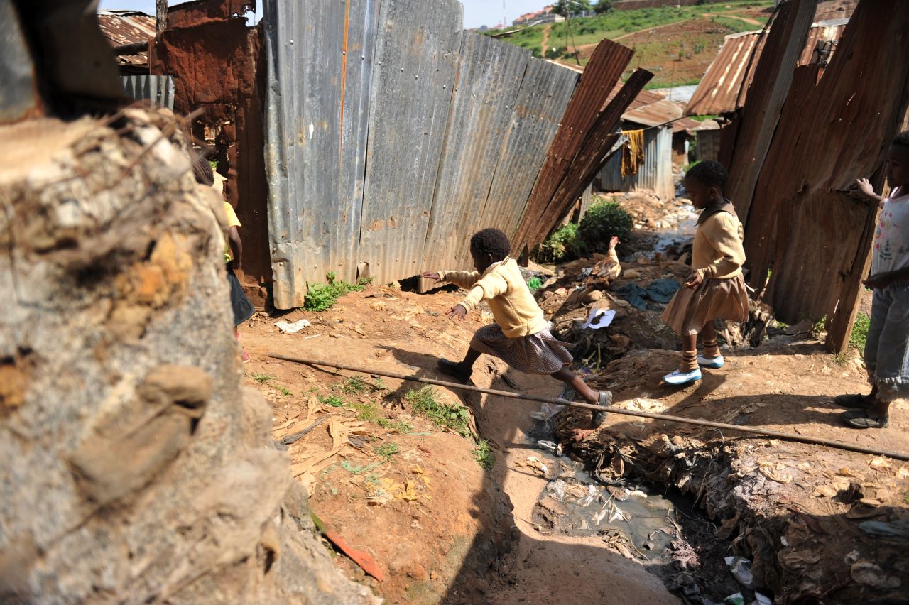 A young girl jumps across a ditch in front of her home in Kibera, the Kenyan squatter settlement that is one of Africa's biggest slums. Children raised in Kibera have no yards or suitable open spaces to play in.