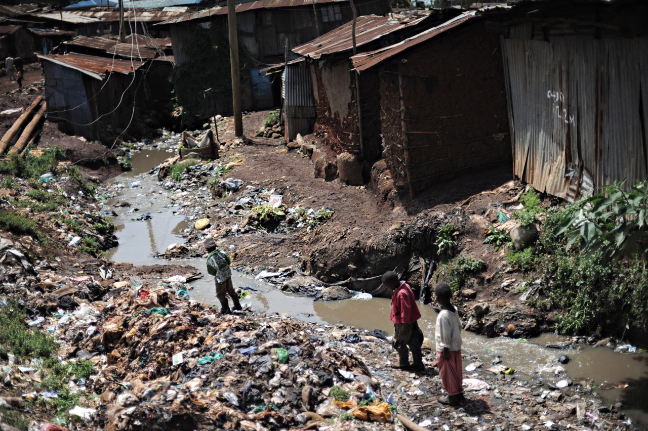 Children in Kibera make their way through the neighborhood across mounds of trash. Kibera suffers from a lack of waste management and santiation services, alongside a host of other critical infrastructure.