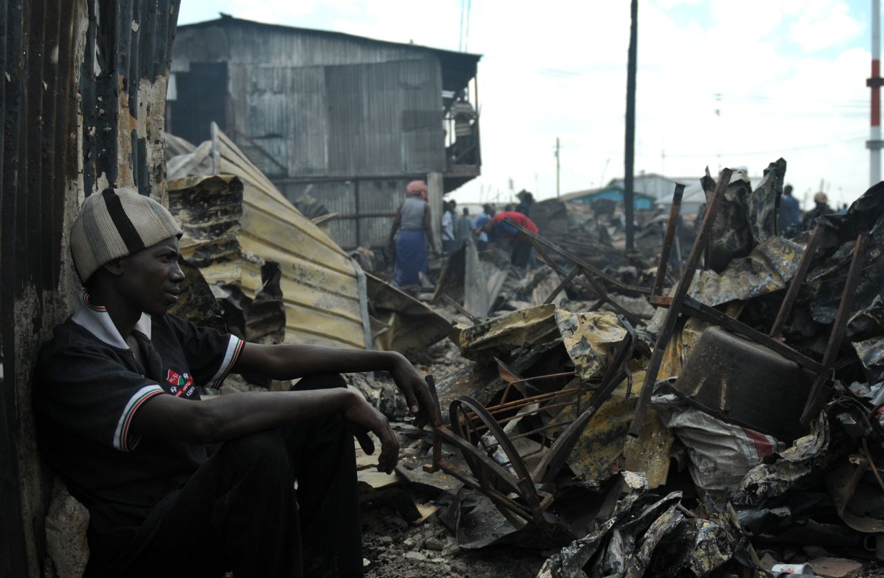 A resident of Kibera sits among the remains of houses that were razed by a fire in March, leaving about 200 families homeless.