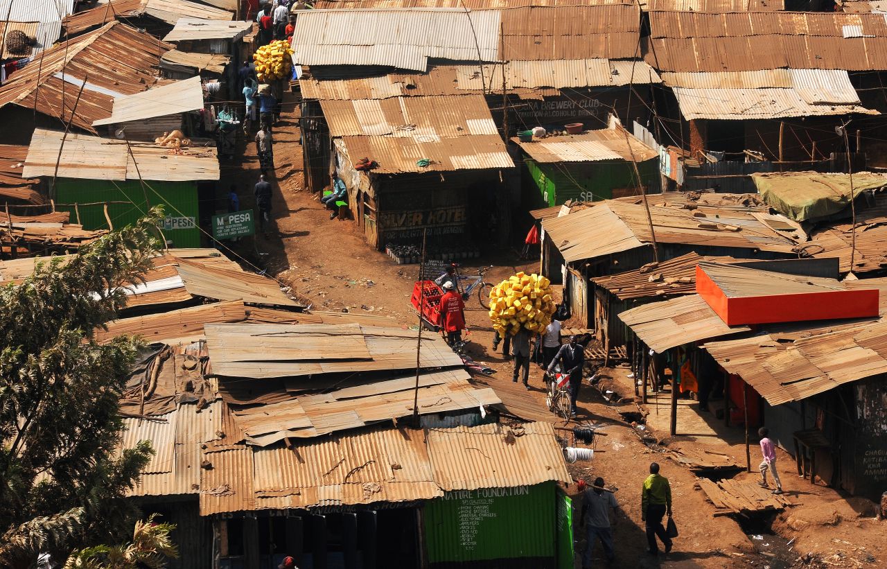 A man carries plastic containers through Kibera on his way to sell them to be recycled. Residents of Kenya's largest slum have to be enterprising to survive given the lack of available jobs.