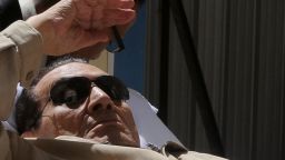Ousted Egyptian president Hosni Mubarak gestures as he is wheeled out of a courtroom following his verdict hearing in Cairo on June 2, 2012. A judge sentenced Mubarak to life in prison after convicting him of involvement in the murder of protesters during the