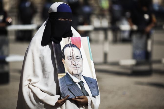 A woman holds a portrait of Mubarak outside the courthouse in Cairo. The image is adorned with a hangman's noose.