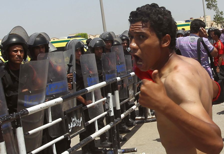 An anti-Mubarak protester shouts before a line of riot police guarding the Cairo courthouse.