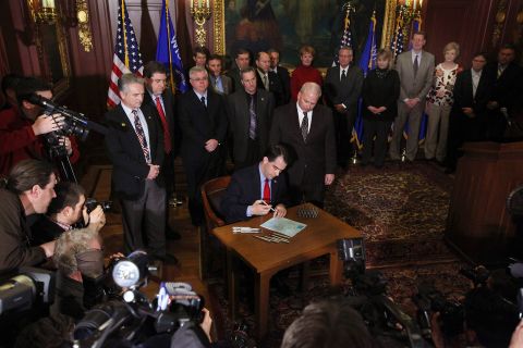 On March 11, 2011, Walker signs a bill that ends the collective bargaining rights of public employees as a measure to close the state's budget shortfall.