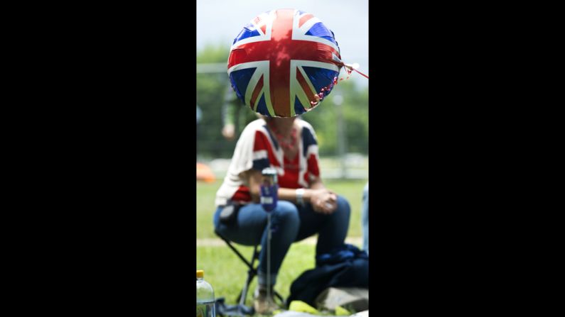 A Union Jack balloon floats in front of a woman wearing a Union Jack T-shirt as she waits for a giant picnic in Hyde Park.