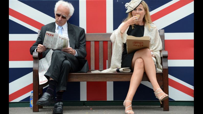 Two racegoiers sit in front of a Union Jack during Derby Day.