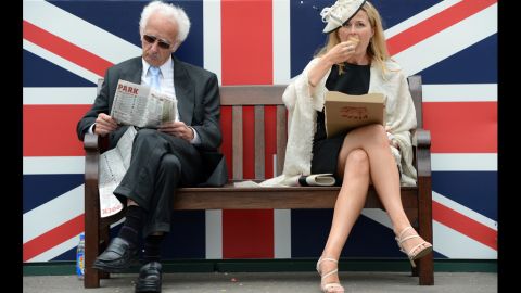 Two racegoiers sit in front of a Union Jack during Derby Day.