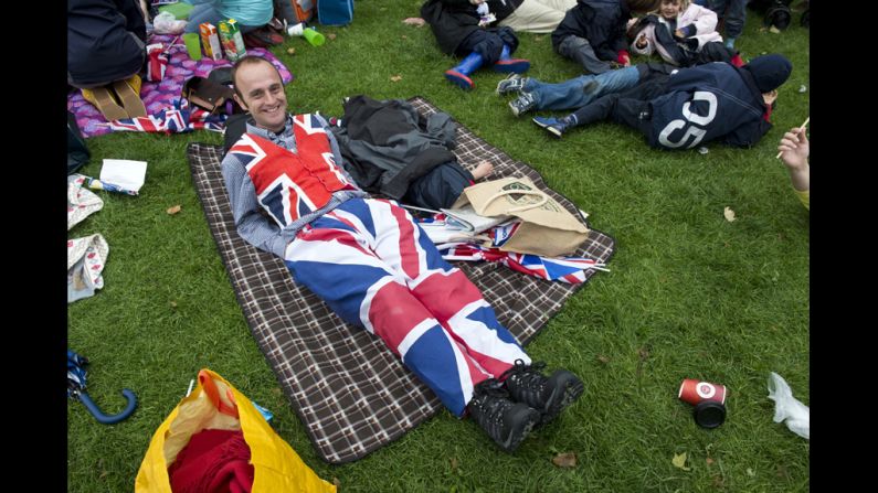 A man watches the River Pageant projected on a screen in Battersea Park.