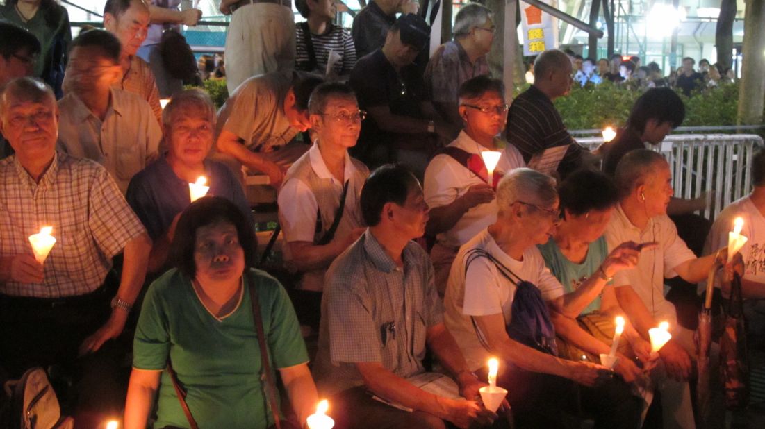 Sitting on bleachers with a group of elderly men holding lit candles in paper cones, 73-year-old Fu Kam-tin says he has been coming to the vigils nearly every year since 1989. Fu, who emigrated from the mainland at age 12, calls the Tiananmen crackdown "the most apparent example in China's history of the strong bullying the weak."  He says he continues to be "very angry and unsettled by these corrupt officials who are harming our country and harming the world."
