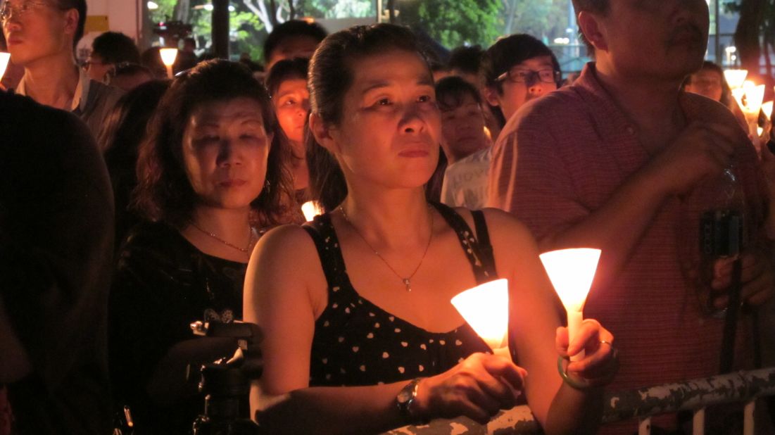 Mourners hold candles placed in paper cones in an outpouring of compassion, a continued sense of injustice, and fear for the future.