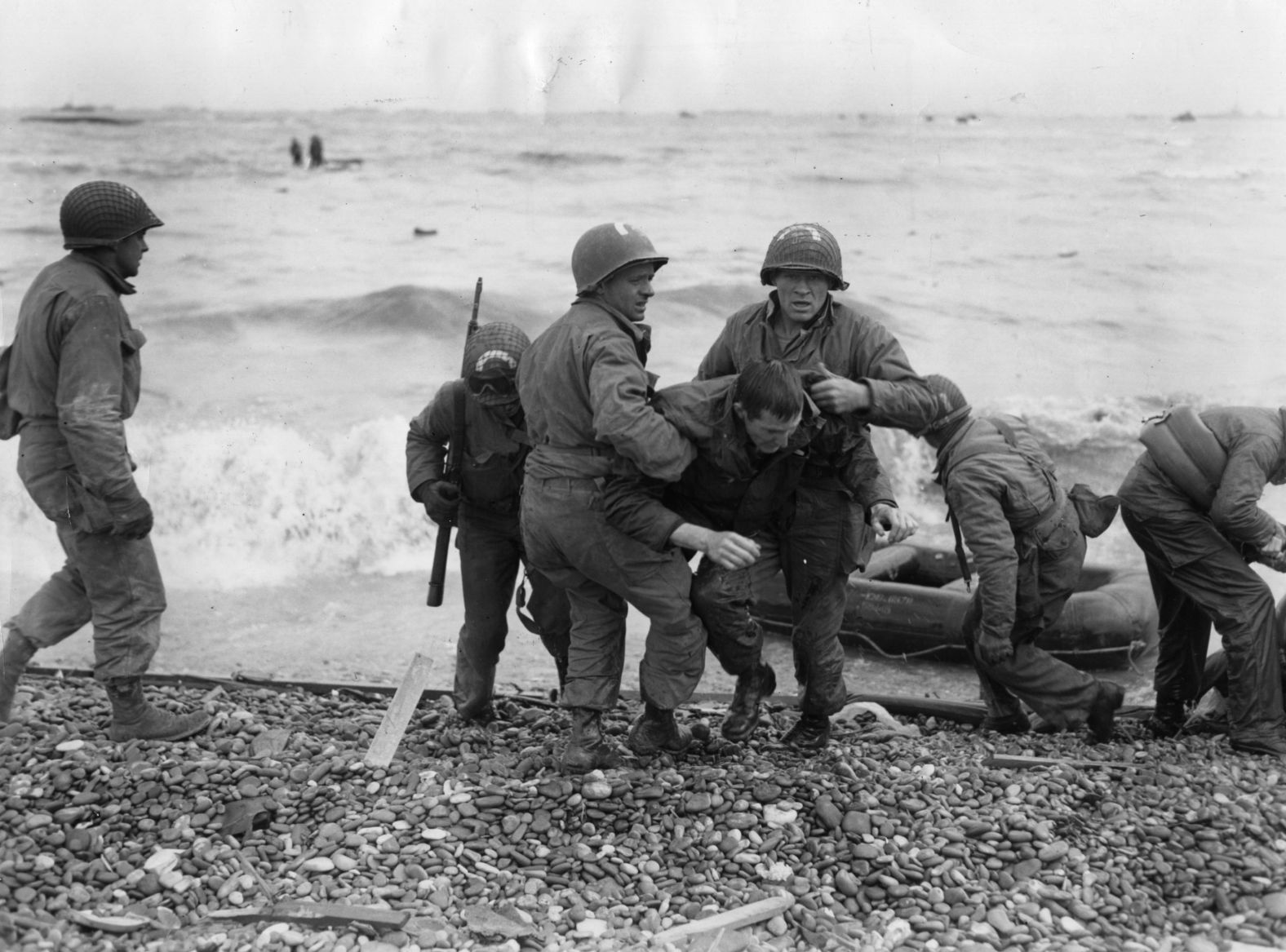 American troops help their injured comrades after their landing craft was fired upon.