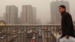 A man walks over a road bridge before high-rise apartments in Beijing on January 17, 2012.