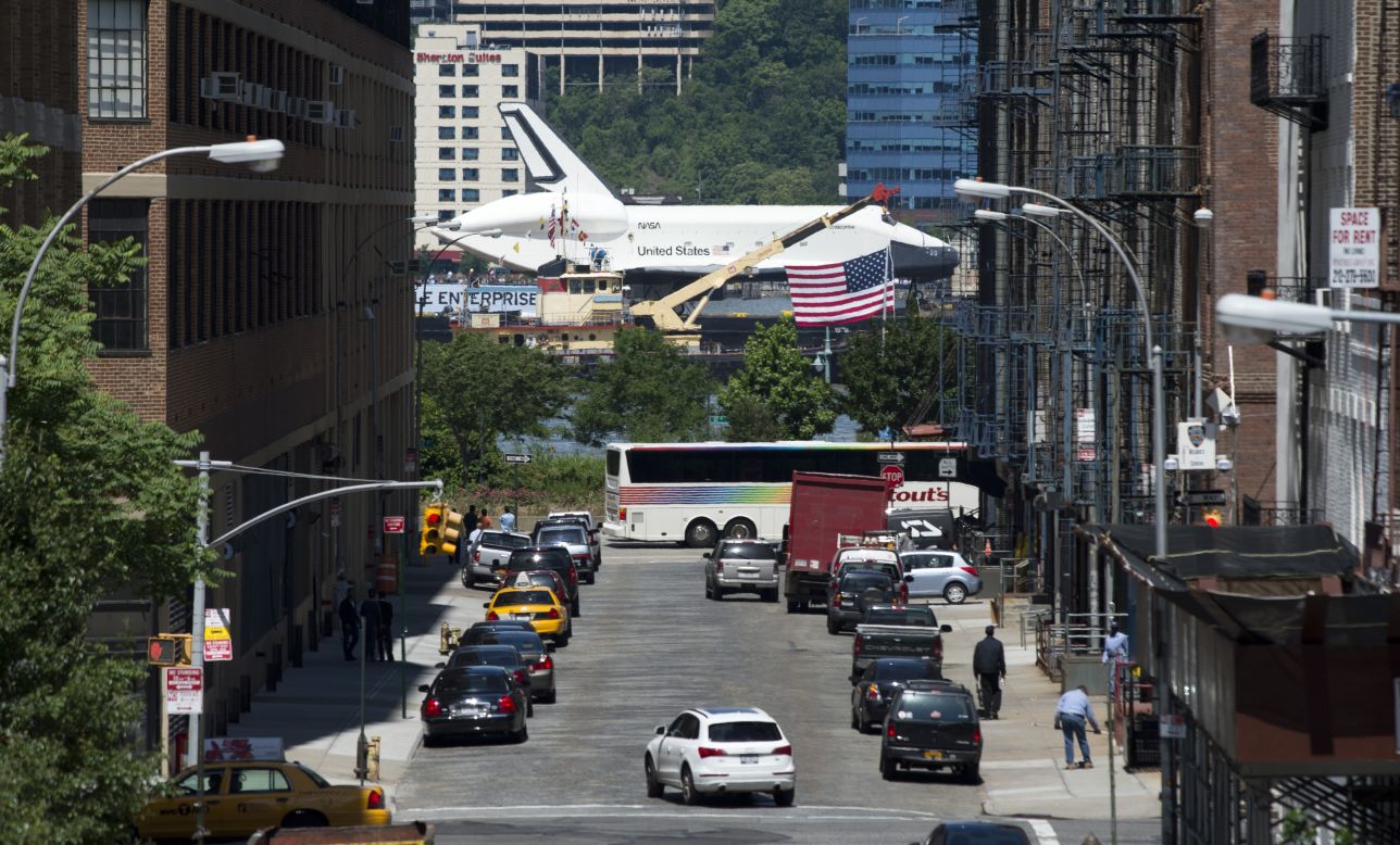 The Enterprise is seen from a busy New York street as it is carried up the river Wednesday.