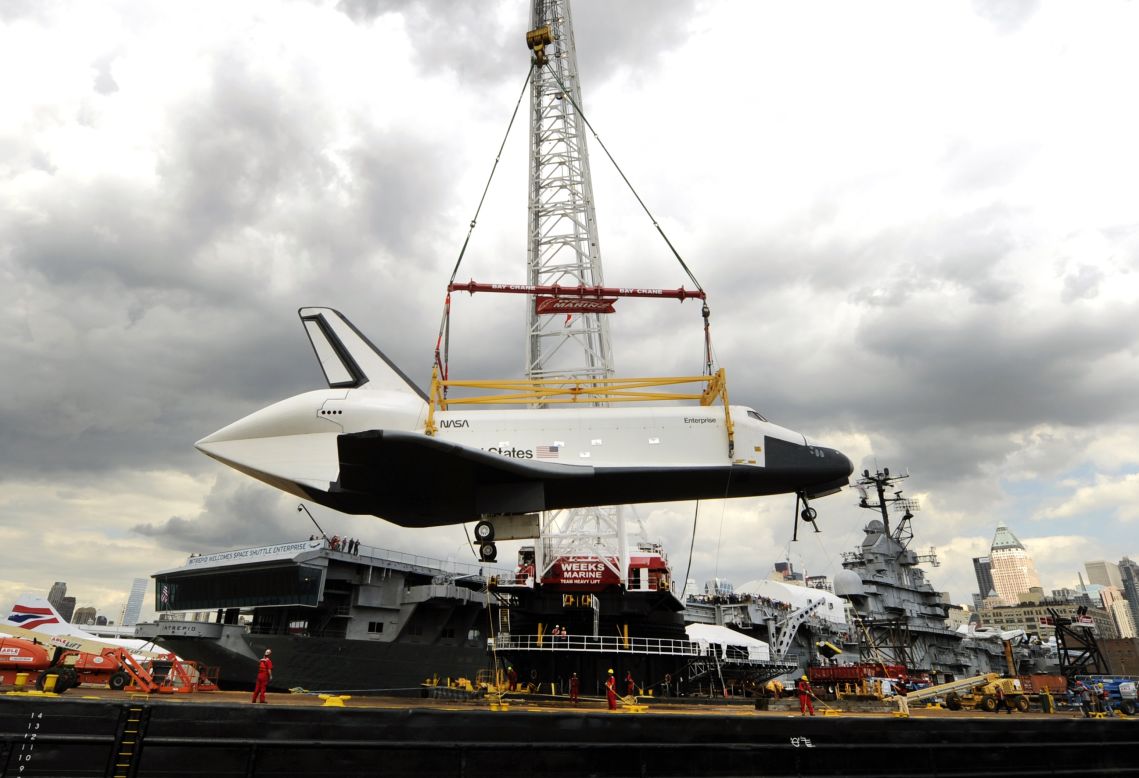 A giant crane carefully swings the Enterprise from the barge that transported it down the Hudson River toward the Intrepid.
