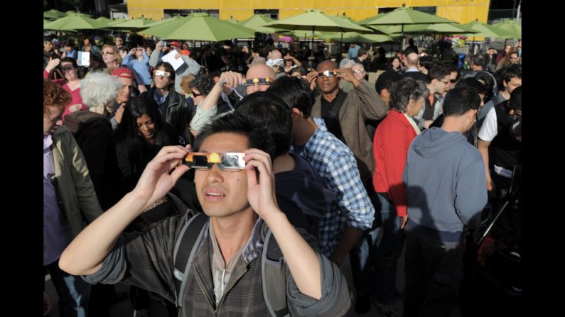 Observers in New York's Riverside Park view the event through special cardboard glasses.