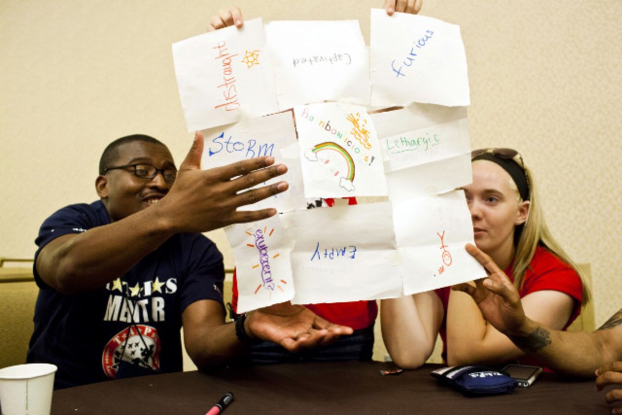 Mentors and teens tape sheets of paper together to express their grief.