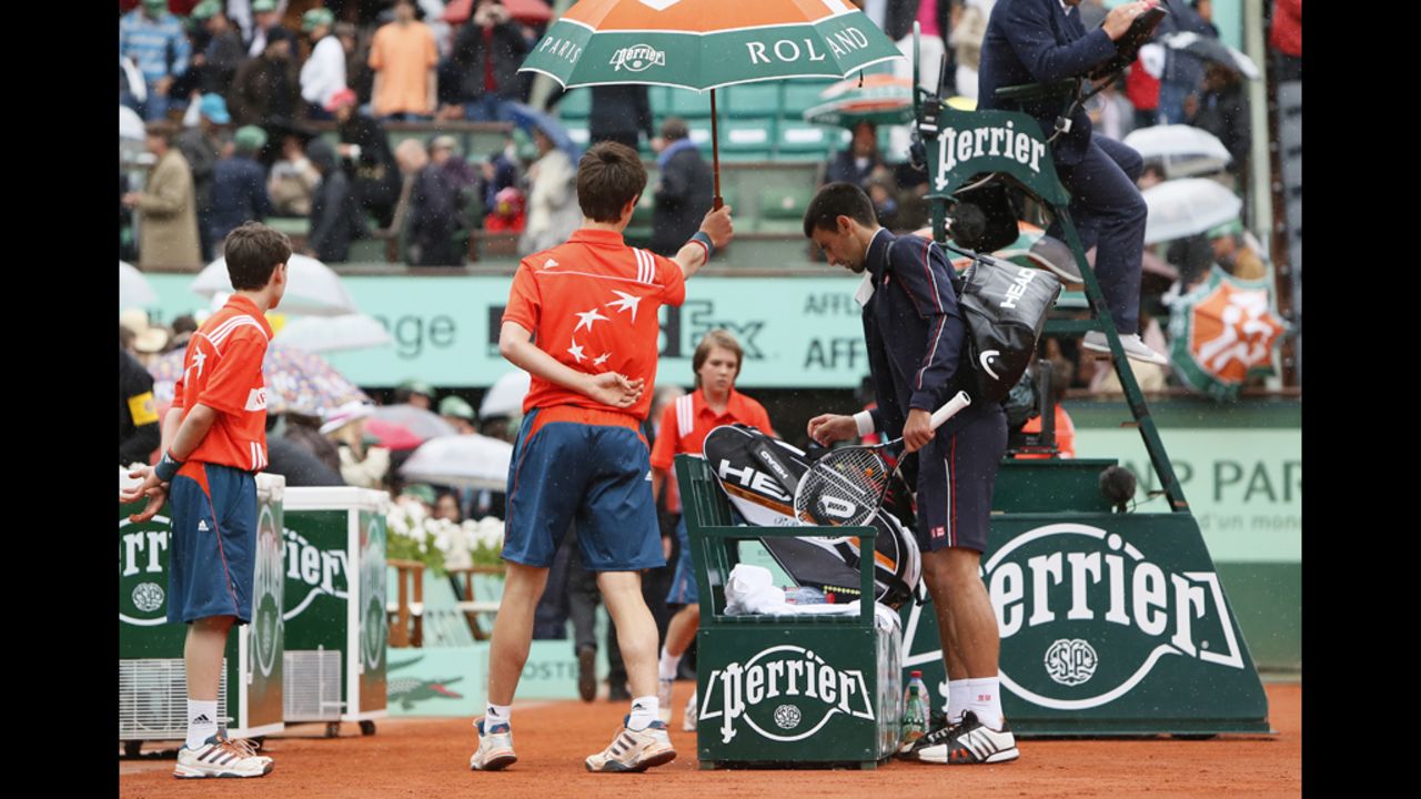 Djokovic leaves the court for a rain delay during the third set after officials haulted play during a downpour. The match was delayed a second time in the fourth set and finished Monday.